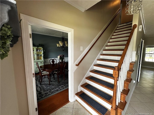 stairs featuring a chandelier, tile patterned flooring, and crown molding