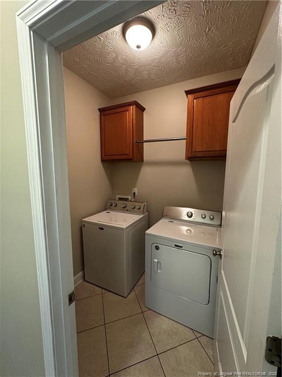 washroom featuring cabinet space, independent washer and dryer, light tile patterned floors, and a textured ceiling