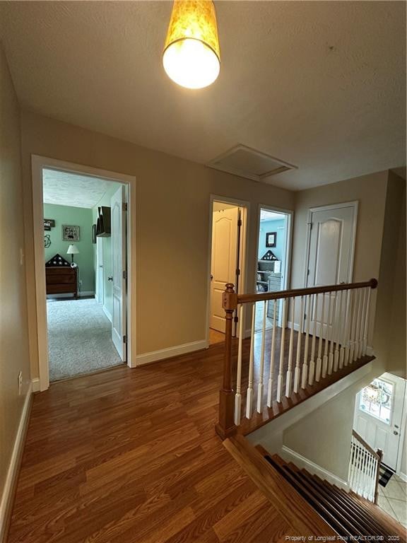 hall featuring an upstairs landing, wood finished floors, and baseboards