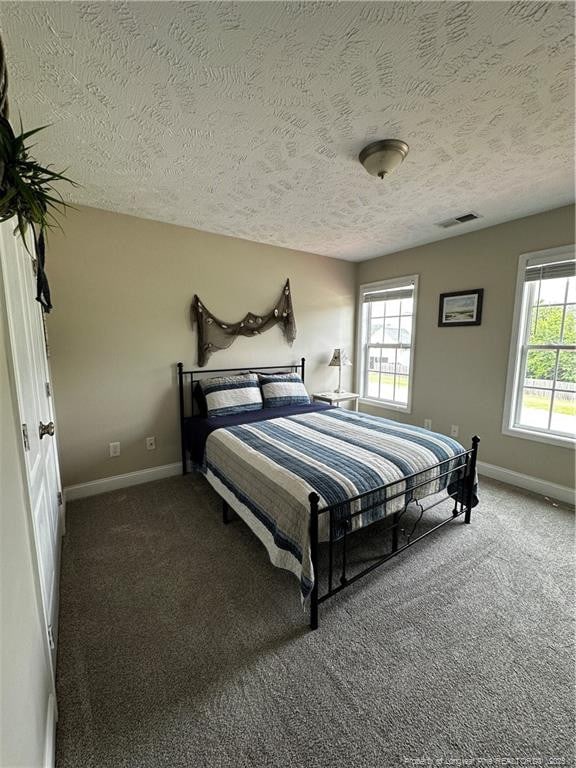 bedroom featuring a textured ceiling, baseboards, and carpet