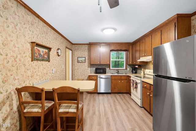 4004 Bamburgh Ln, Apex, NC 27539 - kitchen featuring stainless steel appliances, light countertops, light wood-style flooring, brown cabinets, and crown molding