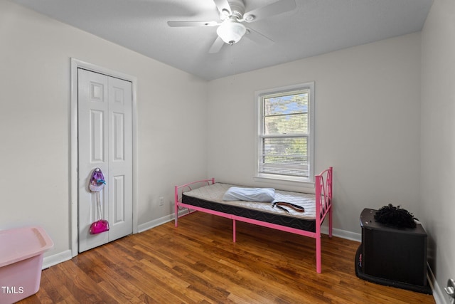 bedroom with wood finished floors, a closet, baseboards, and a ceiling fan