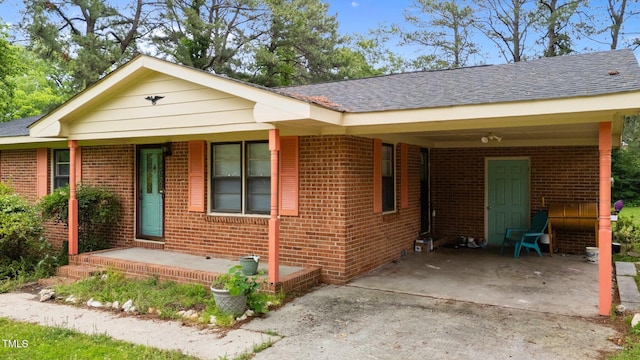 ranch-style home with a carport, brick siding, concrete driveway, and a shingled roof