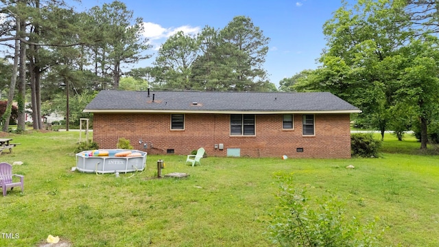 rear view of property with crawl space, a yard, and brick siding