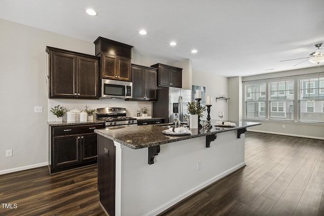 810 Richmont Grove Ln, Apex, NC 27523 - kitchen with appliances with stainless steel finishes, a breakfast bar, dark wood-style floors, an island with sink, and recessed lighting