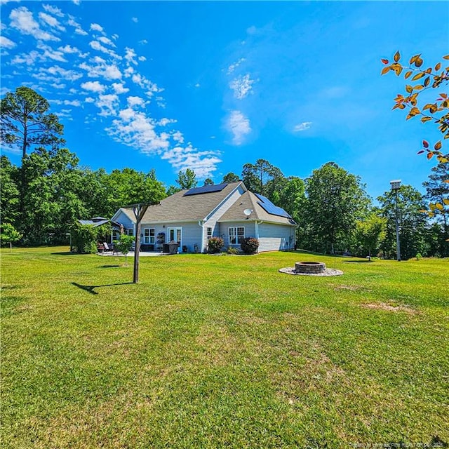 1303 Palestine Rd, Linden, NC 28356 - view of front facade with roof mounted solar panels, a front yard, and an outdoor fire pit
