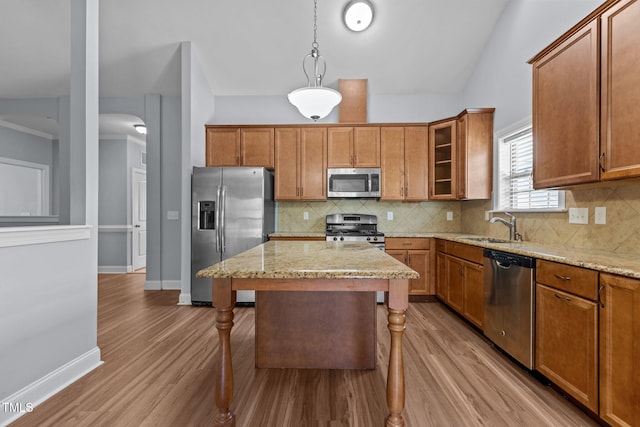 39 Mcguire Ln, Clayton, NC 27527 - kitchen with stainless steel appliances, a sink, a kitchen bar, light stone counters, and brown cabinetry