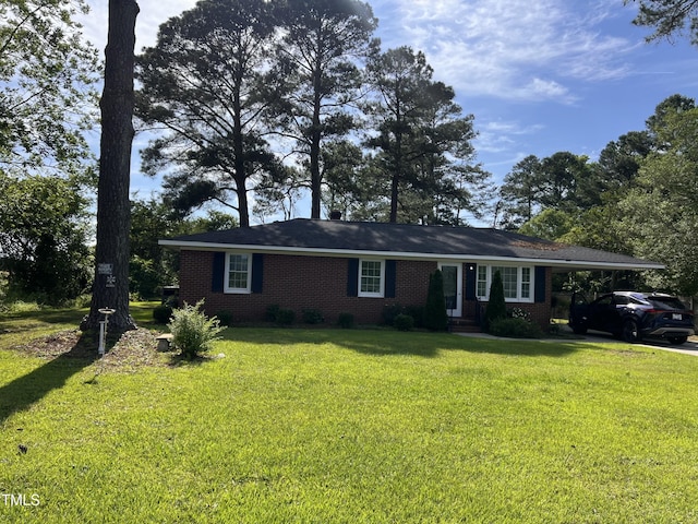 ranch-style home with a front yard, a carport, brick siding, and driveway