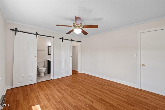 5345 Lamm Rd, Wilson, NC 27893 - unfurnished bedroom with a barn door, light wood-style flooring, ornamental molding, ensuite bathroom, and baseboards