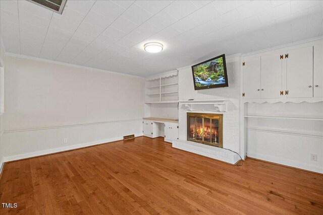 5345 Lamm Rd, Wilson, NC 27893 - unfurnished living room with built in features, wood finished floors, crown molding, a brick fireplace, and baseboards