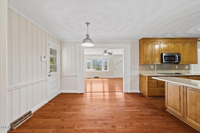 5345 Lamm Rd, Wilson, NC 27893 - kitchen with stainless steel microwave, dark wood finished floors, brown cabinets, tasteful backsplash, and ornamental molding