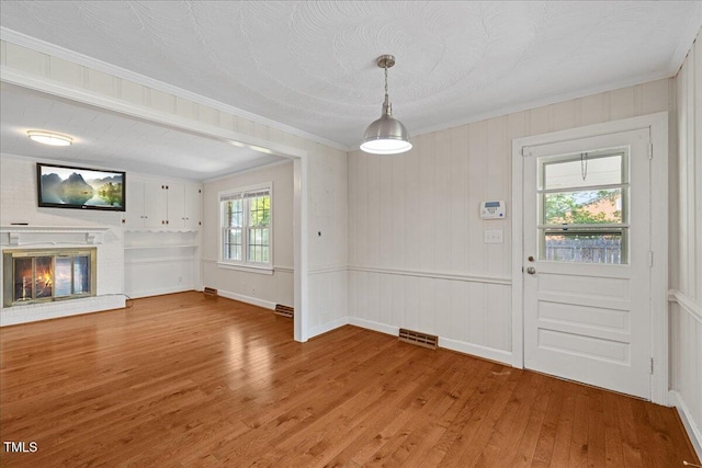 5345 Lamm Rd, Wilson, NC 27893 - unfurnished dining area featuring wood finished floors, crown molding, and a brick fireplace