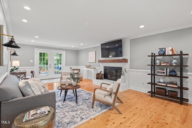 6304 Ansley Ln, Raleigh, NC 27612 - living room featuring ornamental molding, light wood-style flooring, recessed lighting, a fireplace, and a wainscoted wall