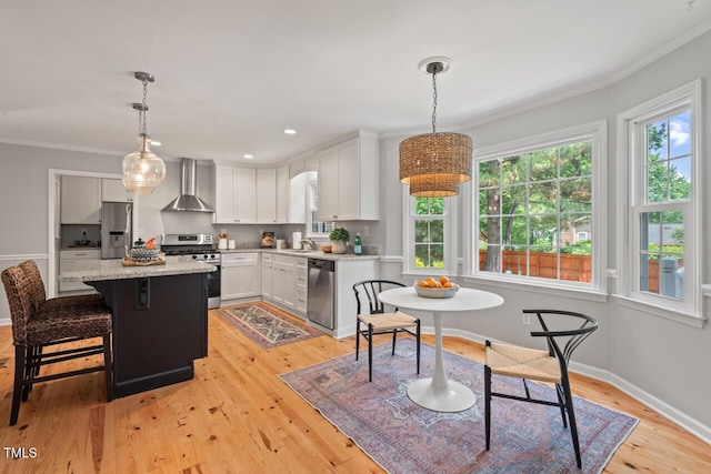 6304 Ansley Ln, Raleigh, NC 27612 - kitchen featuring appliances with stainless steel finishes, wall chimney range hood, white cabinets, light wood-type flooring, and a sink