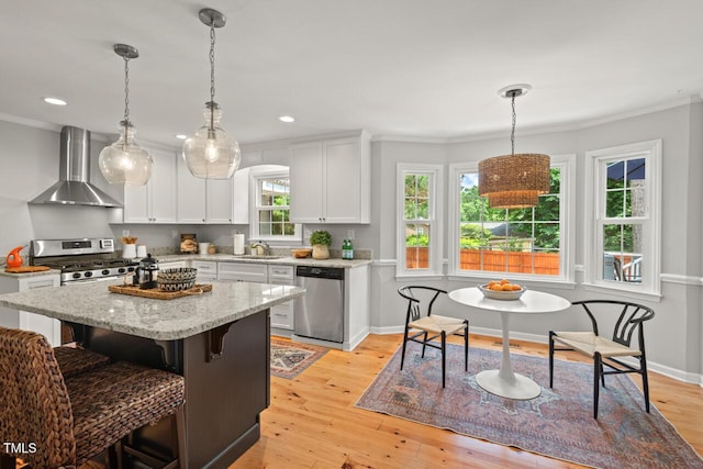 6304 Ansley Ln, Raleigh, NC 27612 - kitchen with appliances with stainless steel finishes, wall chimney exhaust hood, a sink, ornamental molding, and light wood finished floors