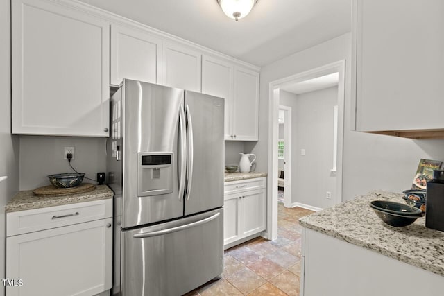 6304 Ansley Ln, Raleigh, NC 27612 - kitchen with stainless steel fridge, white cabinets, stone finish flooring, and light stone counters
