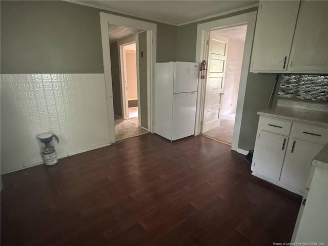 unfurnished dining area featuring dark wood finished floors and crown molding