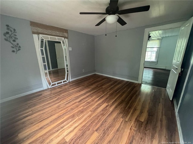 spare room featuring a ceiling fan, wood finished floors, a baseboard radiator, and baseboards