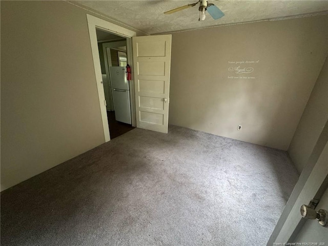 unfurnished bedroom with freestanding refrigerator, carpet, a textured ceiling, and a ceiling fan