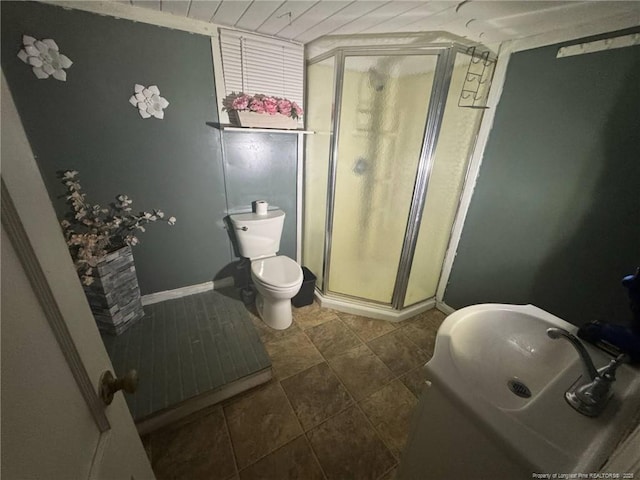 bathroom featuring a stall shower, baseboards, toilet, and tile patterned floors
