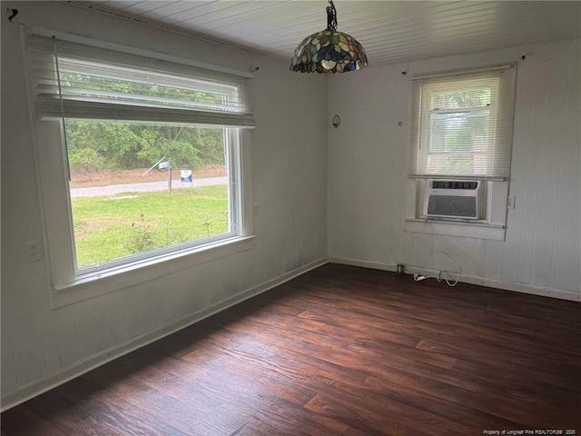 unfurnished dining area with dark wood-style flooring, cooling unit, and baseboards