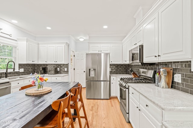 2408 Fordcrest Dr, Apex, NC 27502 - kitchen featuring appliances with stainless steel finishes, a sink, white cabinets, decorative backsplash, and ornamental molding