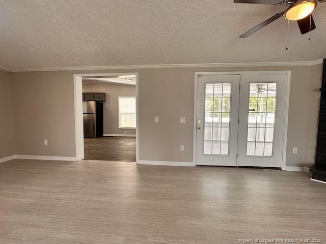 spare room with wood finished floors, baseboards, ceiling fan, crown molding, and a textured ceiling