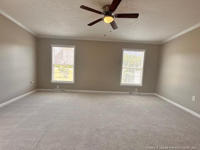 unfurnished room featuring a textured ceiling, ornamental molding, plenty of natural light, baseboards, and carpet floors
