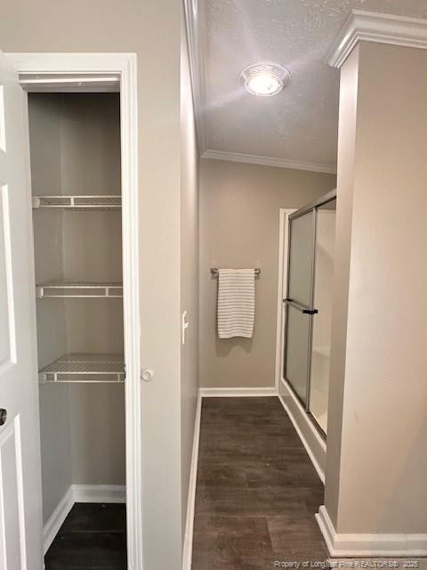 full bath featuring ornamental molding, a stall shower, wood finished floors, baseboards, and a textured ceiling
