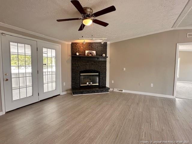 unfurnished living room featuring a textured ceiling, wood finished floors, crown molding, ceiling fan, and baseboards