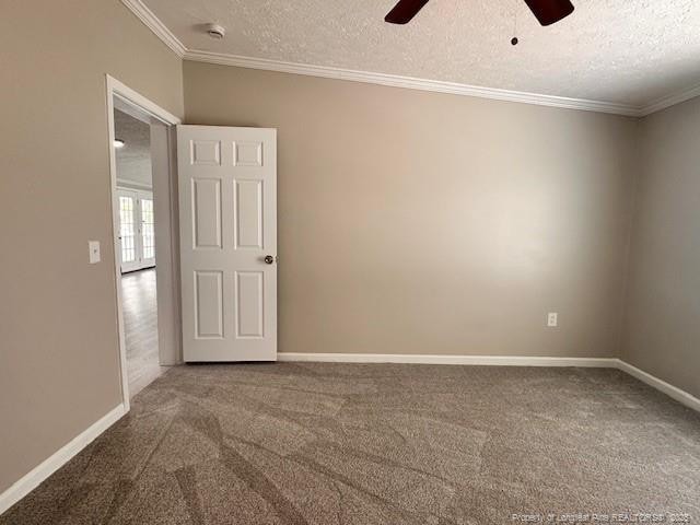 carpeted spare room featuring crown molding, ceiling fan, a textured ceiling, baseboards, and a smoke detector