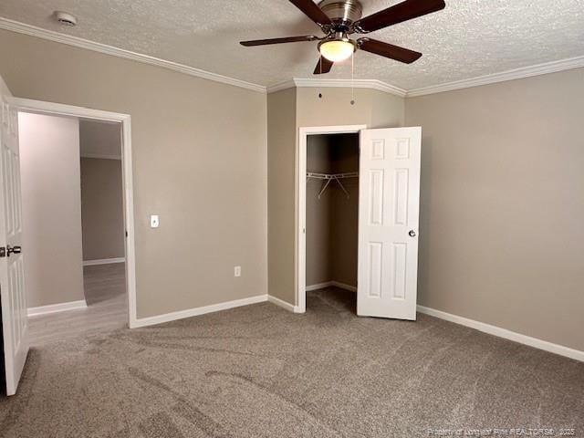 unfurnished bedroom with a textured ceiling, carpet, a closet, ornamental molding, and baseboards