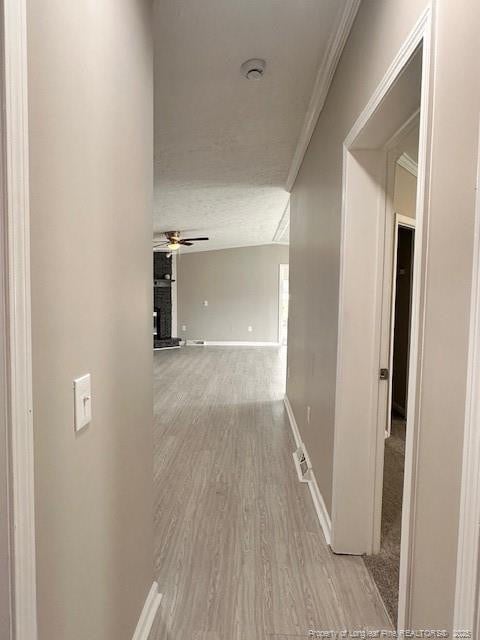 hallway featuring wood finished floors, crown molding, and baseboards