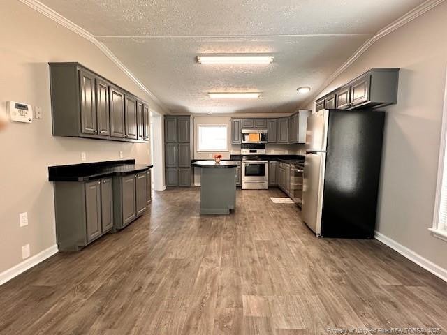 kitchen featuring appliances with stainless steel finishes, dark countertops, a textured ceiling, gray cabinets, and a kitchen island