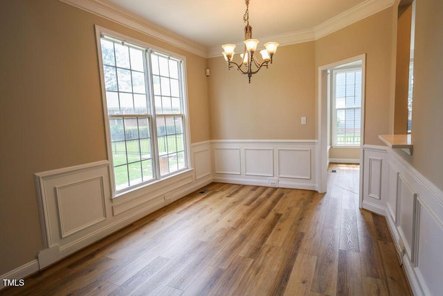 10 London Way, Spring Lake, NC 28390 - unfurnished dining area with healthy amount of natural light, a chandelier, wood finished floors, a wainscoted wall, and ornamental molding