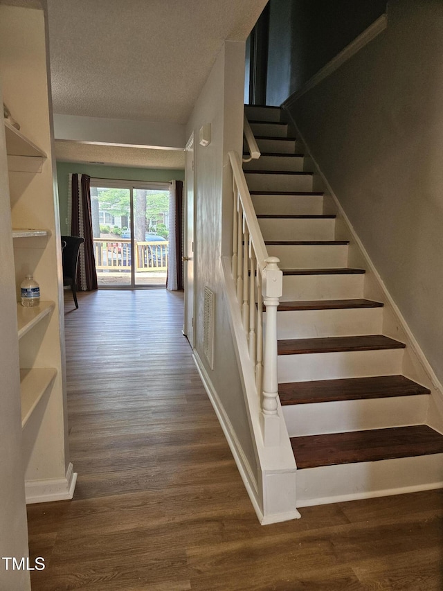7719 Kingsberry Ct, Raleigh, NC 27615 - stairway featuring wood finished floors, a textured ceiling, and baseboards