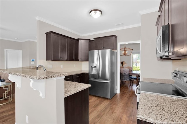 341 Woodington Rd, Hope Mills, NC 28348 - kitchen featuring stainless steel appliances, a peninsula, dark brown cabinets, wood finished floors, and backsplash