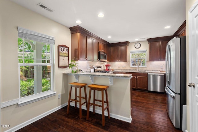 3002 Bartlett Cir, Hillsborough, NC 27278 - kitchen with appliances with stainless steel finishes, a peninsula, backsplash, dark wood-style floors, and light stone counters
