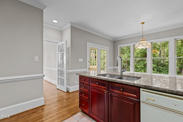 kitchen featuring a sink, reddish brown cabinets, dishwasher, healthy amount of natural light, and crown molding