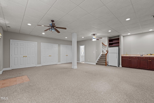 unfurnished living room with ceiling fan, light carpet, stairs, a paneled ceiling, and recessed lighting