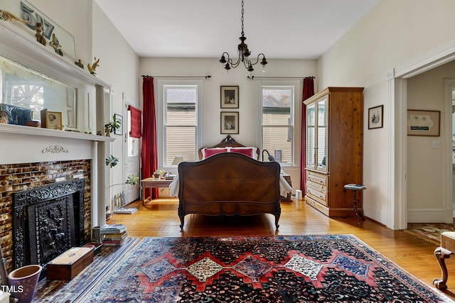 517 N E St, Raleigh, NC 27604 - bedroom featuring light wood finished floors, a chandelier, a tile fireplace, and baseboards