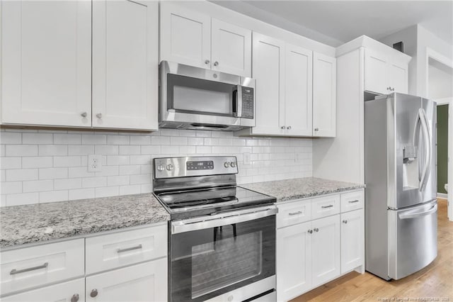 607 Rempstone Ln, Fayetteville, NC 28311 - kitchen featuring appliances with stainless steel finishes, light wood-style flooring, white cabinets, light stone countertops, and tasteful backsplash
