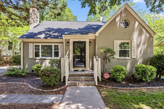 1304 N Duke St, Durham, NC 27701 - view of front facade featuring a chimney, a shingled roof, and brick siding