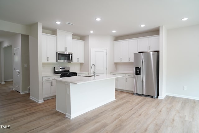 2106 Cherry Creek Rd, Haw River, NC 27258 - kitchen featuring stainless steel appliances, a sink, decorative backsplash, light wood-style floors, and a center island with sink