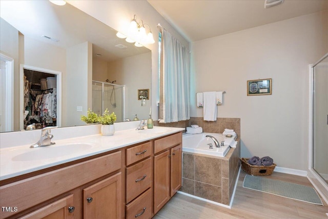 6512 Blalock Forest Dr, Willow Springs, NC 27592 - bathroom featuring a shower stall, wood finished floors, double vanity, a garden tub, and a walk in closet
