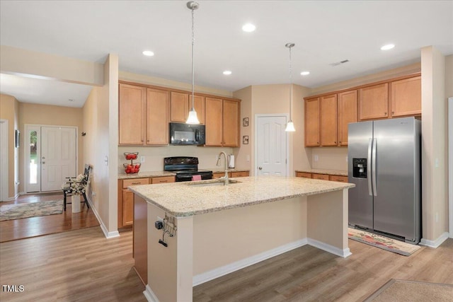 6512 Blalock Forest Dr, Willow Springs, NC 27592 - kitchen with black appliances, light wood-style floors, a center island with sink, a sink, and light stone countertops