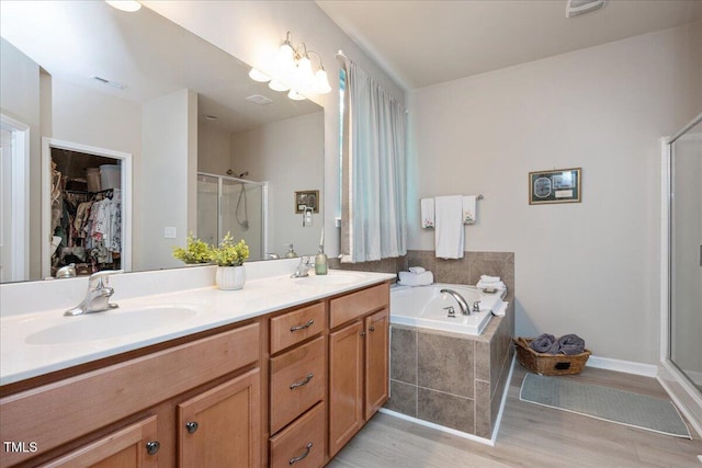 6512 Blalock Forest Dr, Willow Springs, NC 27592 - full bathroom featuring a stall shower, wood finished floors, a walk in closet, double vanity, and a garden tub