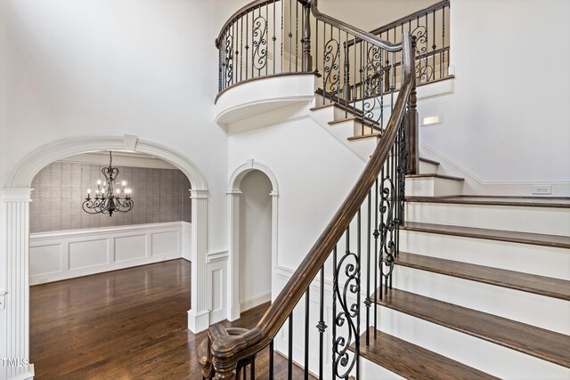3908 Chaumont Dr, Apex, NC 27539 - stairway with a decorative wall, a chandelier, arched walkways, wood finished floors, and ornate columns
