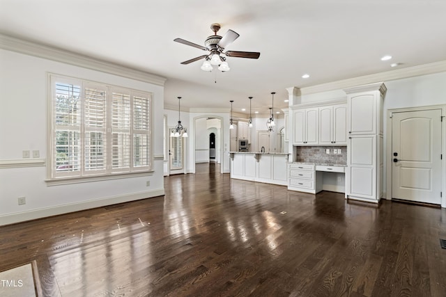 3908 Chaumont Dr, Apex, NC 27539 - unfurnished living room featuring a ceiling fan, ornamental molding, dark wood-type flooring, baseboards, and arched walkways