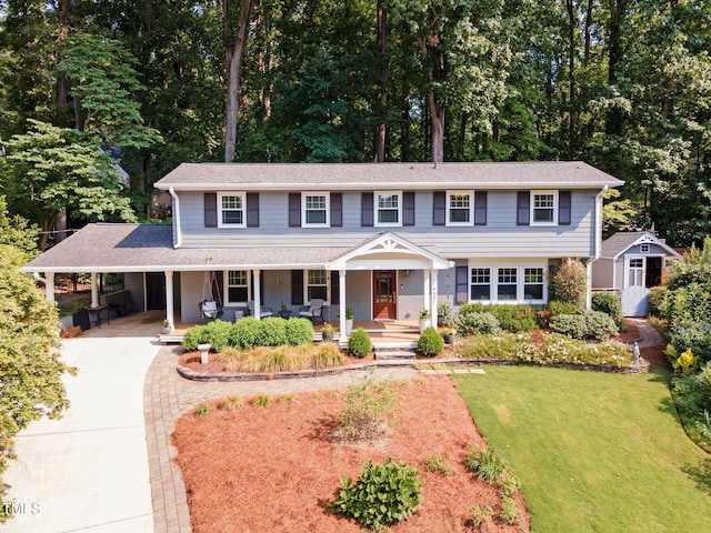 4021 Converse Dr, Raleigh, NC 27609 - view of front facade featuring a porch, driveway, a front lawn, a carport, and view of wooded area